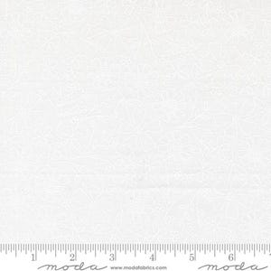 May include: White fabric with a floral pattern. The design features detailed outlines of various flowers and leaves, creating a delicate and textured appearance. The fabric is measured in inches along the bottom edge.