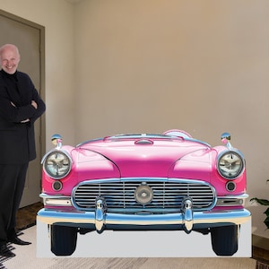 May include: A pink vintage car with chrome accents and a white background. The car is a convertible with the top down.