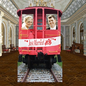 May include: A red train car with a banner that reads "Just Married" with a car and heart graphic. A bride and groom are inside the car. The train car is on tracks inside a large room with a piano.