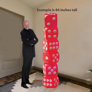 May include: A stack of six large red dice with white dots, standing 84 inches tall. The dice are stacked on top of each other, with the top die showing a six. The dice are in a room with a person standing next to them.