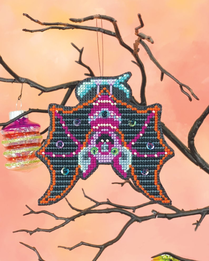 Beaded cross stitch Halloween ornament of a bat hanging upside down