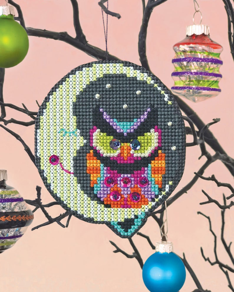 A beaded cross stitch ornament kit of an owl sitting on a crescent moon