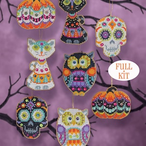 May include: A collection of Halloween-themed cross-stitch ornaments, including pumpkins, cats, owls, and sugar skulls. Each ornament is intricately detailed with vibrant colors and bead accents, suspended against a purple backdrop with bare tree branches.