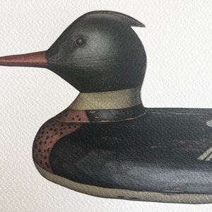 May include: A black and brown wooden duck decoy with a red beak. The duck has a white band around its neck and a detailed pattern on its body.