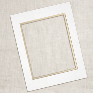May include: A white mat with a gold inner border. The mat is designed to hold a photo or artwork.