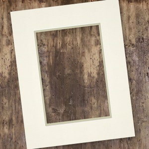 May include: A white mount with a rectangular aperture, showing a woodgrain background.