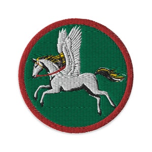 Peut inclure: Un écusson brodé vert et rouge représentant un cheval ailé blanc avec une bride dorée, sur un fond vert.