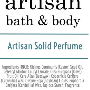 May include: Artisan Solid Perfume with a green leaf logo and the text "artisan bath & body". The ingredients are listed below: Ricinus Communis (Castor) Seed Oil, Cetearyl Alcohol, Lauryl Laurate, Olea Europaea (Olive) Fruit Oil, Cera Alba (Beeswax), Copernicia Cerifera (Carnauba) Wax, Glycine Soja (Soybean) Lipids, Euphorbia Cerifera (Candelilla) Wax, Tapioca Starch, Fragrance. The website address is artisanbathandbody.com and artisanbathandbody.etsy.com.