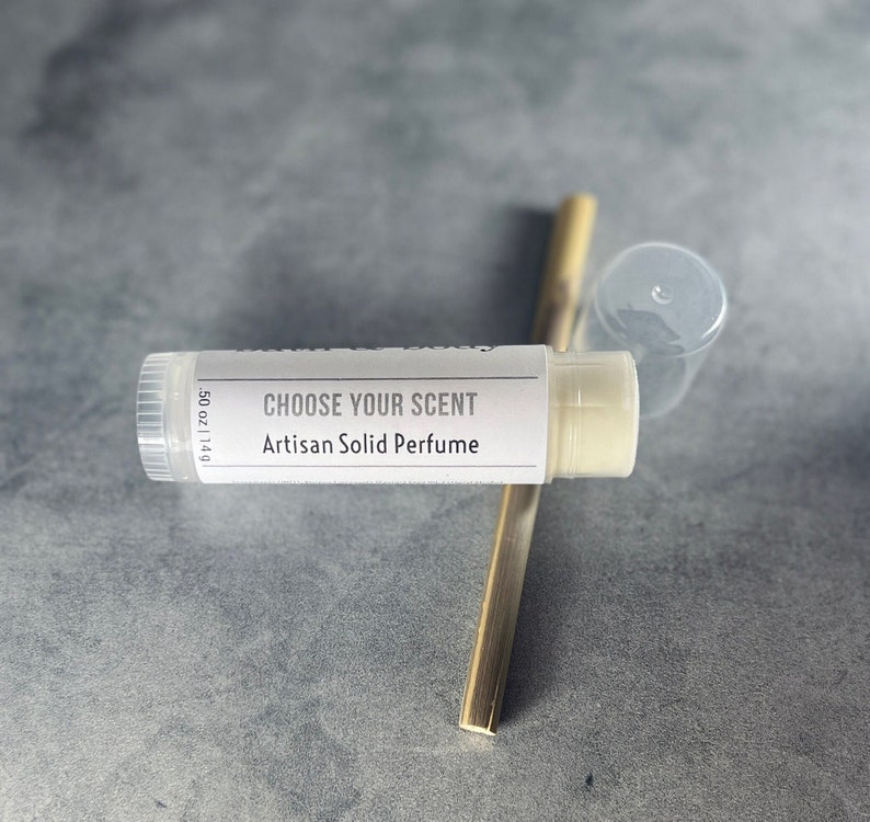 May include: A white tube of solid perfume with the text "CHOOSE YOUR SCENT Artisan Solid Perfume" and "0.5 oz | 14g".