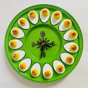 May include: A green serving platter with a clock face in the center and 12 deviled eggs arranged around the clock face.