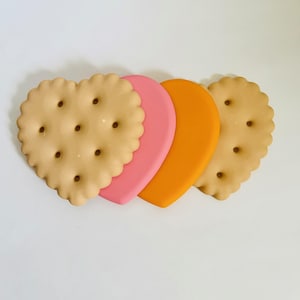 May include: Three heart-shaped silicone cookie cutters, one beige, one pink and one orange.