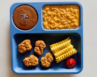 May include: A blue divided tray with a meal of chicken nuggets, french fries, macaroni and cheese, and chocolate pudding.