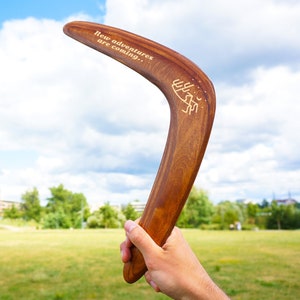 Personalized dark brown wooden boomerang in hand