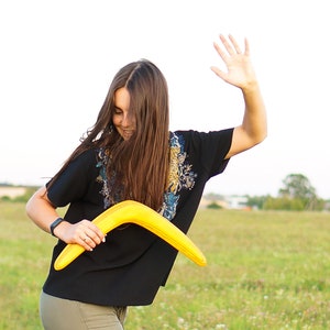 women holds yellow boomerang in right hand