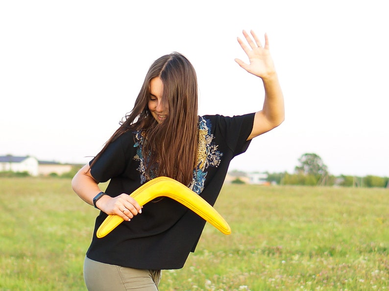 women holds yellow boomerang in right hand