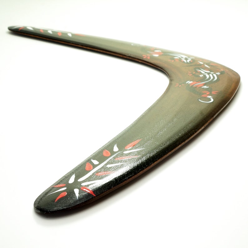 May include: A green wooden boomerang with red and white painted designs. The boomerang is curved and has a smooth surface.