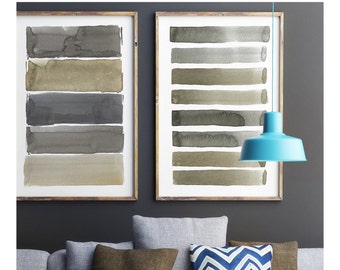 Puede incluir: Dos pinturas de acuarela enmarcadas con pinceladas horizontales en tonos grises y beige cuelgan sobre un sofá gris con cojines marrones y azules. Una lámpara colgante turquesa cuelga del techo.