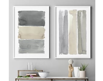 May include: Two framed watercolor art prints. One features three horizontal blocks of gray and beige tones. The other has vertical stripes in similar colors. The prints are displayed above a metal and marble shelf with decorative items.