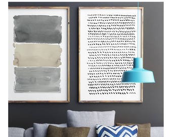 May include: Modern living room decor featuring a gray sofa with brown and blue accent pillows. Two framed abstract art pieces hang on the dark gray wall. A turquoise pendant light hangs above a white coffee table with a black metal bowl.