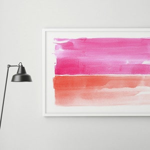 May include: A framed abstract watercolor painting with a white border. The artwork features two horizontal bands of color: a vibrant pink at the top and a coral-orange at the bottom. A gray bench with a dark wooden frame sits below the artwork.
