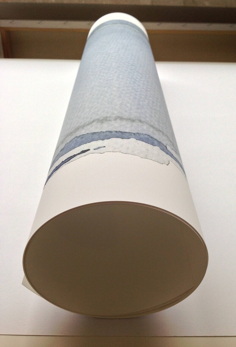 May include: Rolled artwork featuring a watercolor design. The cylindrical piece displays a light blue and gray textured pattern with blue and black horizontal bands. The bottom edge is a cream color, and the end is a tan color.