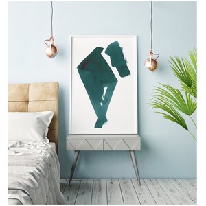 May include: A framed abstract art print with teal brushstrokes on a white background. The artwork is displayed on a gray nightstand with angled legs, next to a bed with a beige headboard. Copper-colored pendant lights hang from the ceiling.