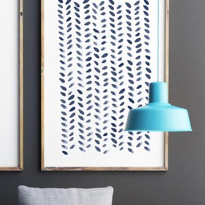 May include: A framed art print featuring a repeating pattern of blue leaf-like shapes on a white background. The artwork is in a wooden frame and hangs on a gray wall. A turquoise pendant light hangs in front of the artwork.