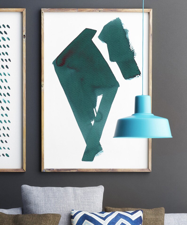 May include: Two framed abstract art prints with wooden frames. One print features a pattern of teal dots, and the other showcases a teal geometric shape. A turquoise pendant lamp hangs in the foreground, adding a pop of color.