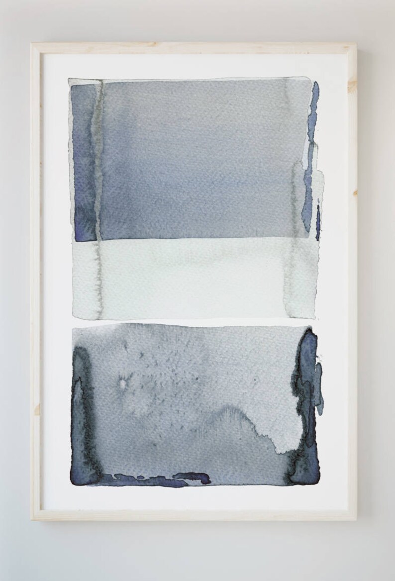May include: Abstract watercolor painting in a light wood frame. The artwork features three horizontal bands of color: a top and bottom section in shades of blue-gray, and a white band in the middle. The painting has a textured, artistic quality.