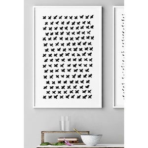 May include: Two framed abstract art prints. The first print features a grid of black brushstroke crosses on a white background. The second print, to the right, has a vertical line of black brushstrokes. Both are in white frames.