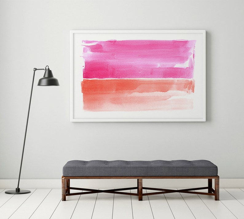 May include: A framed abstract watercolor painting with a white border. The artwork features two horizontal bands of color: a vibrant pink at the top and a coral-orange at the bottom. A gray bench with a dark wooden frame sits below the artwork.