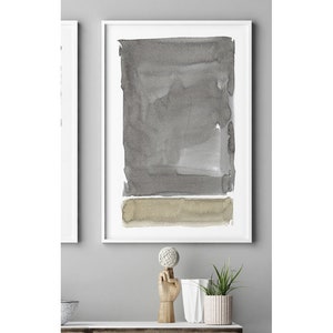 May include: Abstract watercolor art print in a white frame. The artwork features a large gray rectangular shape above a smaller, horizontal tan shape. The watercolor effect gives a soft, textured appearance. The art print is displayed on a white shelf.