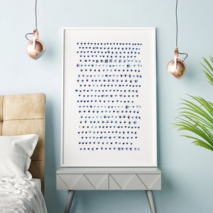 May include: A framed art print featuring a pattern of blue hearts and other shapes on a white background. The artwork is displayed on a gray nightstand in a bedroom setting, with a bed and hanging lights visible.
