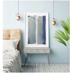 May include: A framed abstract watercolor painting with vertical stripes in shades of blue and gray. The artwork is displayed on a gray nightstand with silver legs, next to a bed with a beige headboard. Copper-colored pendant lights hang above.