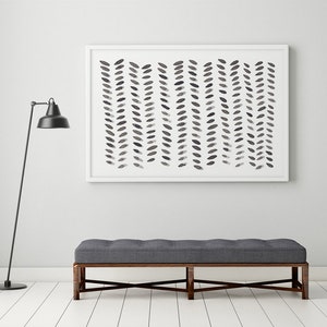 May include: A framed abstract art print with a white border features a pattern of vertical rows of dark gray leaf-like shapes. Below, a gray upholstered bench with a dark wooden frame sits on white wooden flooring. A black floor lamp stands to the left.