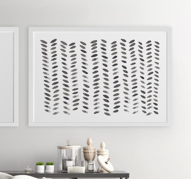 May include: Abstract art print in a white frame. The artwork features a pattern of vertical rows of dark gray, leaf-like shapes on a white background. The print is displayed above a table with decorative items.