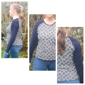 K&ouml;nnte beinhalten: Ein lang&auml;rmliges Shirt mit einem blau-wei&szlig; gestreiften Muster mit kleinen Ankermotiven. Das Shirt hat einen Raglan-&Auml;rmel mit blauem &Auml;rmel und einem wei&szlig;-blau gestreiften Oberk&ouml;rper.