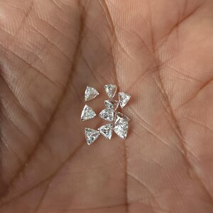 group of calibrated trillion cut natural diamonds shown in hand, multiple 3x3mm triangle side stones displayed for matching sets, jewelry supply for rings earrings and pendants, F G near colorless VVS VS