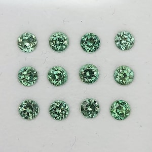 Puede incluir: Una taza de cerámica blanca con un asa negra y el texto "But First, Coffee" en negro, con una fuente de estilo manuscrito. La taza está sobre una superficie blanca.