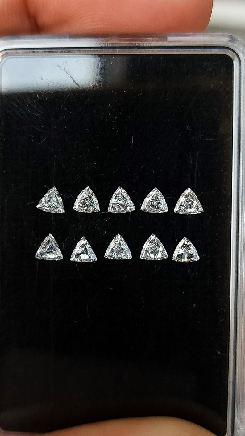 natural diamond trillion side stones in a case close up, calibrated 3x3mm triangle diamonds shown in rows for matched sets, crisp corners and bright reflections, fine jewelry supply F G VVS VS