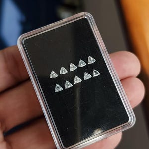 angled view of a case with trillion cut natural diamonds on a black card, calibrated 3x3mm (3.00x3.00mm) triangle stones for matched pairs and sets, clean symmetry and bright sparkle, natural daylight