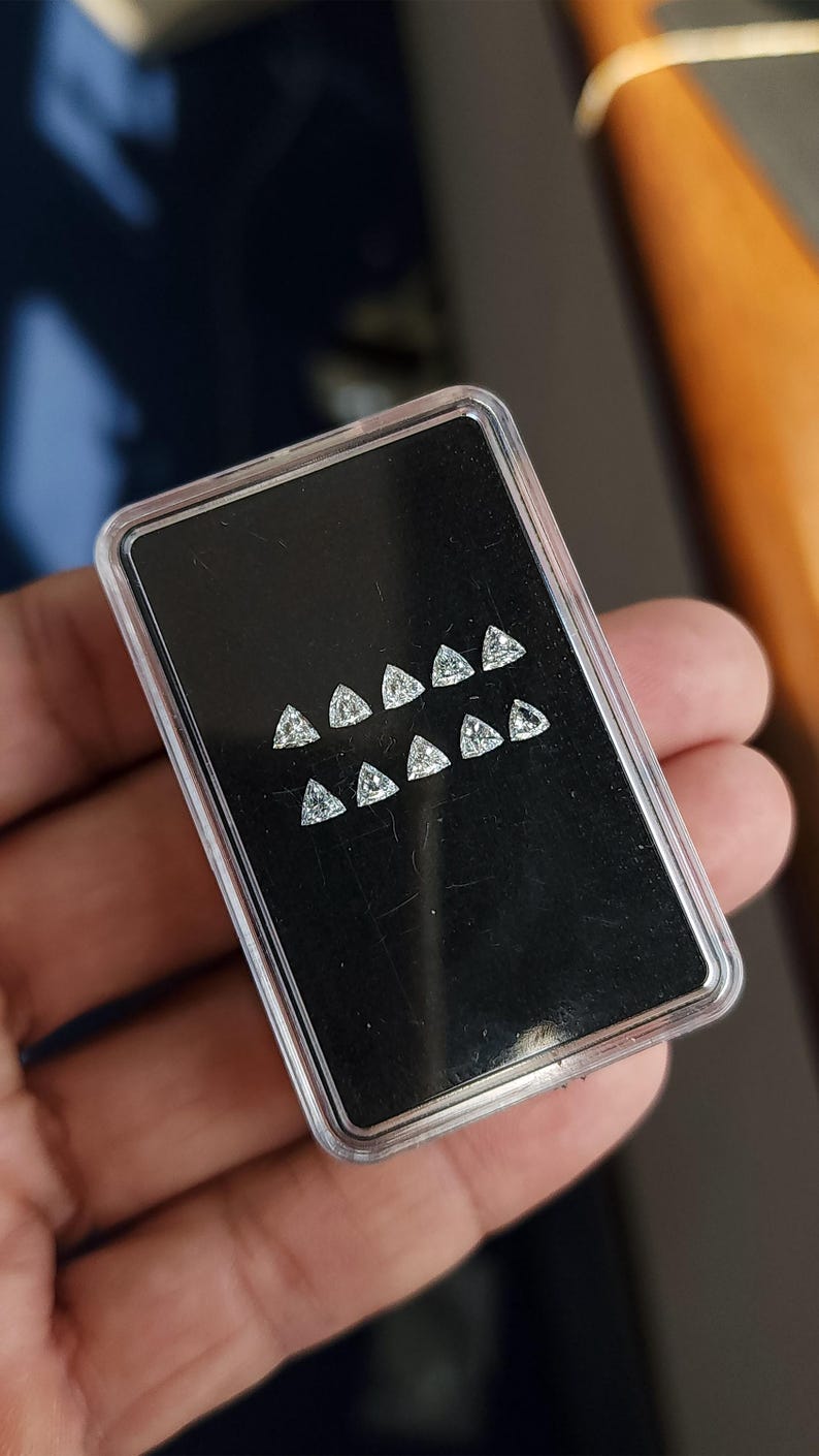 angled view of a case with trillion cut natural diamonds on a black card, calibrated 3x3mm (3.00x3.00mm) triangle stones for matched pairs and sets, clean symmetry and bright sparkle, natural daylight