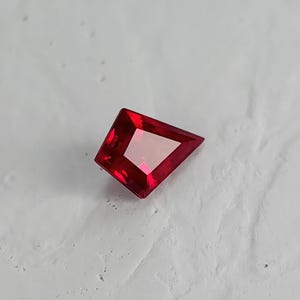 Face-up view of the loose kite cut ruby on a light background. The strong geometric outline and saturated pigeon blood red tone are clearly visible. Perfect proportions and flawless clarity make it an ideal center stone for a bespoke ring or pendant. This lab grown ruby is precision cut and ready to be set in fine jewelry.