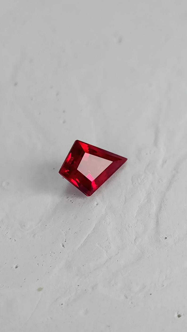 Face-up view of the loose kite cut ruby on a light background. The strong geometric outline and saturated pigeon blood red tone are clearly visible. Perfect proportions and flawless clarity make it an ideal center stone for a bespoke ring or pendant. This lab grown ruby is precision cut and ready to be set in fine jewelry.