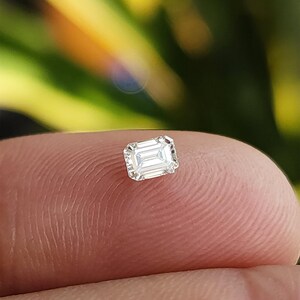 Close up of the same gem box tilted in the hand, highlighting the sparkle and symmetry of the natural emerald cut diamonds against the dark background.