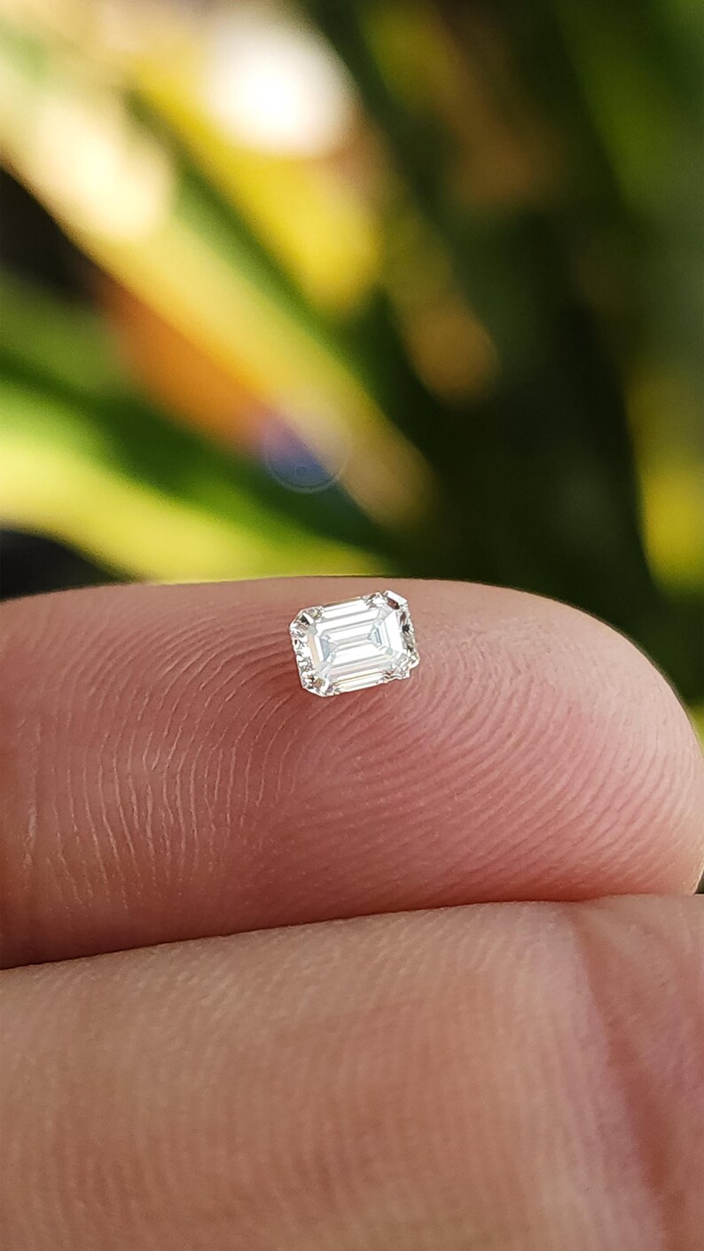 Close up of the same gem box tilted in the hand, highlighting the sparkle and symmetry of the natural emerald cut diamonds against the dark background.