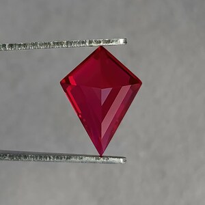 Reverse view of the lab created ruby in tweezers, showing the pavilion architecture and clean facet alignment of the kite cut. The stone displays intense red without brown or pink shift. Flawless clarity and elite polish make it suitable for luxury bridal jewelry, heirloom reinterpretations, or custom orders where exact size and shape matter.