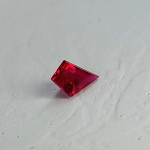 Top view of the loose kite cut pigeon blood red ruby placed on a neutral background. The stone displays deep, even saturation and a sharp modern silhouette perfect for designer jewelry layouts. With flawless clarity, AAA grade quality, and elite Thai polish, this lab grown ruby is ready to serve as a luxury focal gem in a fully custom setting.