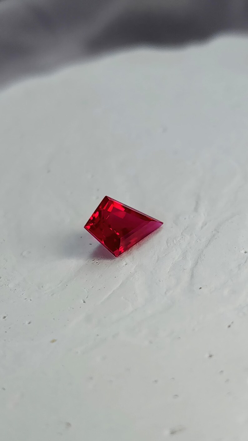 Top view of the loose kite cut pigeon blood red ruby placed on a neutral background. The stone displays deep, even saturation and a sharp modern silhouette perfect for designer jewelry layouts. With flawless clarity, AAA grade quality, and elite Thai polish, this lab grown ruby is ready to serve as a luxury focal gem in a fully custom setting.