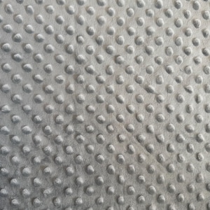 May include: Close-up of a soft, gray fabric with a textured surface. The fabric is covered in evenly spaced, raised, rounded bumps, creating a tactile and visually interesting pattern. The material appears plush and comfortable, suitable for blankets or other cozy items.